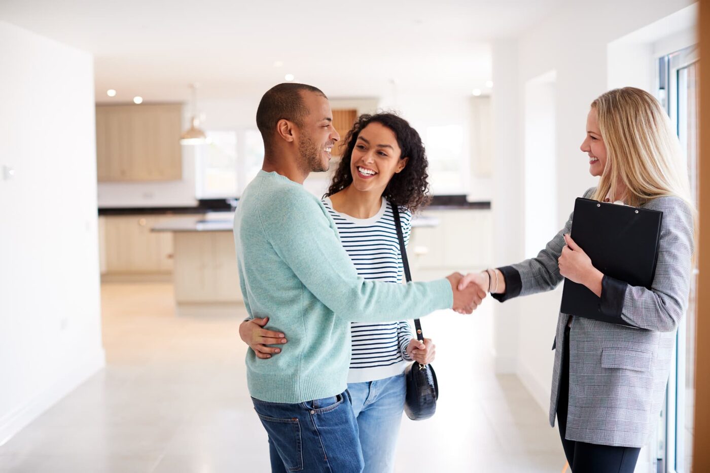 Couple shaking hands with their agent inside their new home
